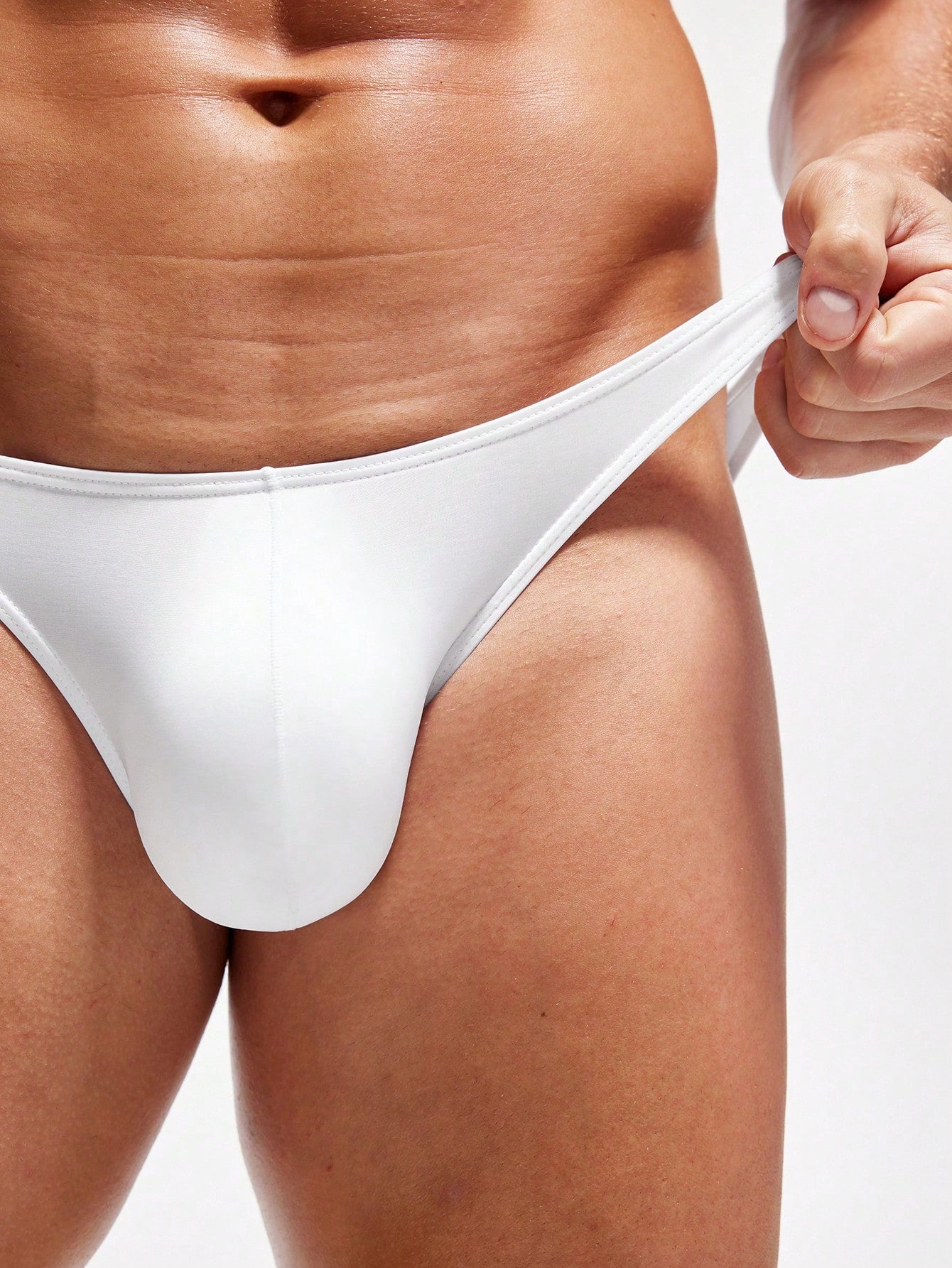 Men's white low-rise triangle briefs with colorblock styling, semi-sheer knitted fabric, and a close-fitting brief silhouette.