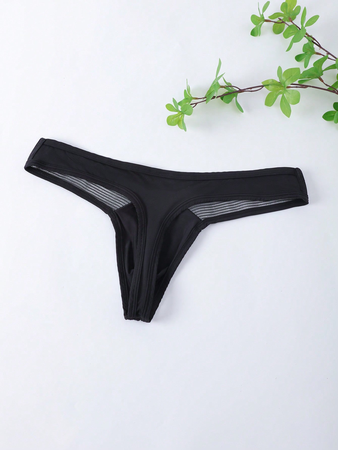 Men's black low-rise mesh T-back thong briefs with colorblock pattern and patched details