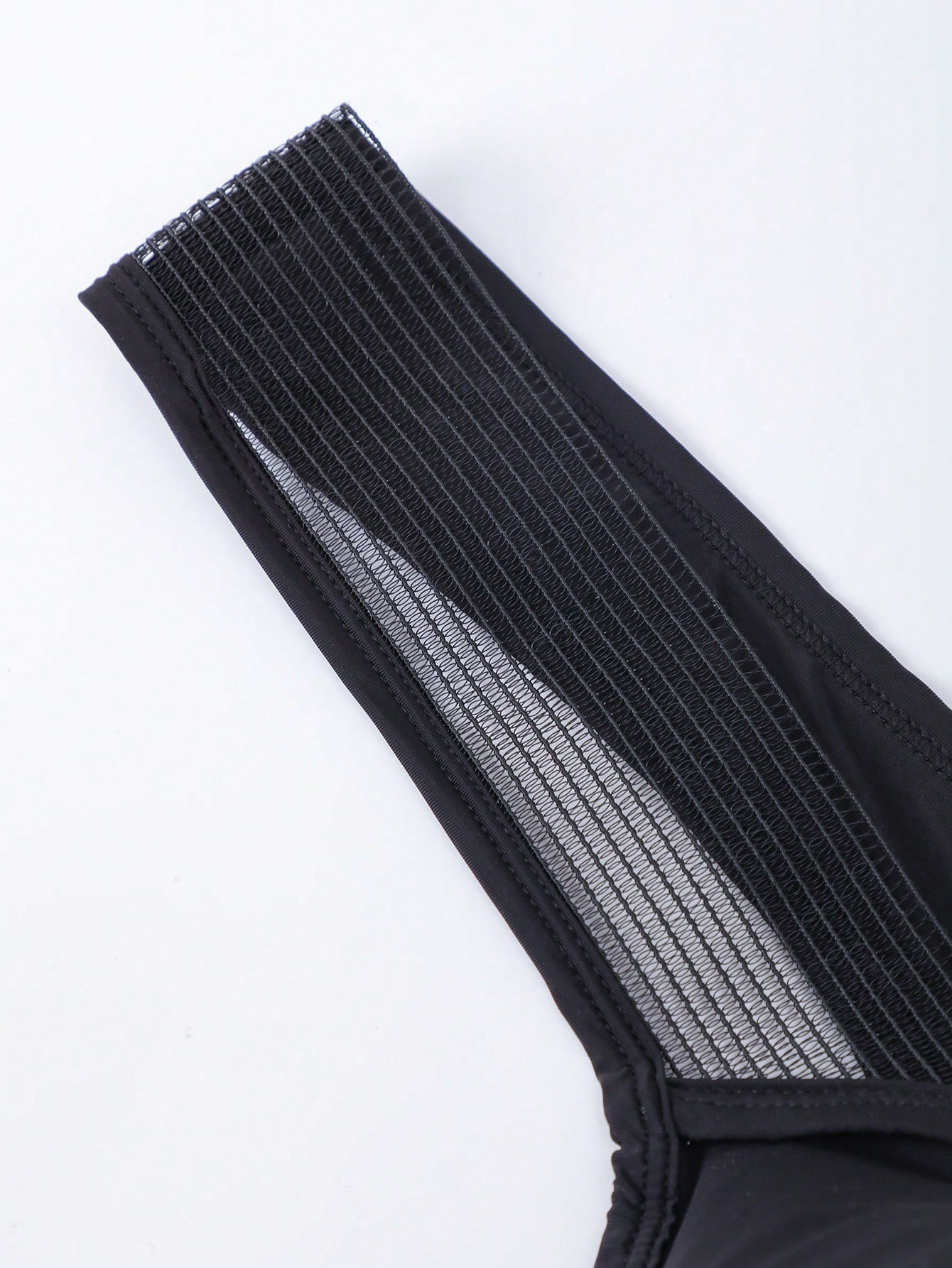 Men's black low-rise mesh T-back thong briefs with colorblock pattern and patched details