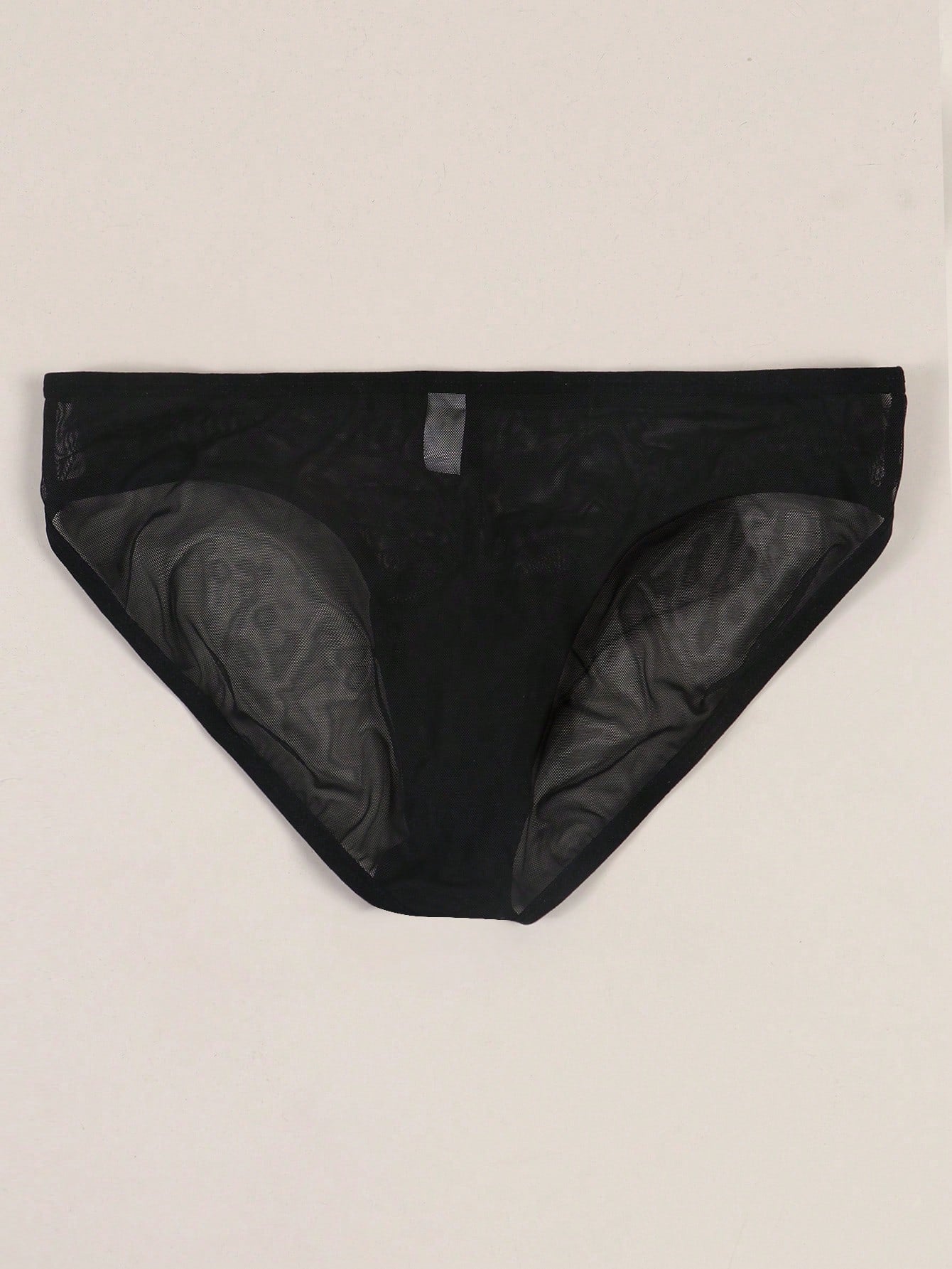 Men's black semi-sheer mesh thong with heart eye print pattern, low-rise cut, and breathable knitted fabric.