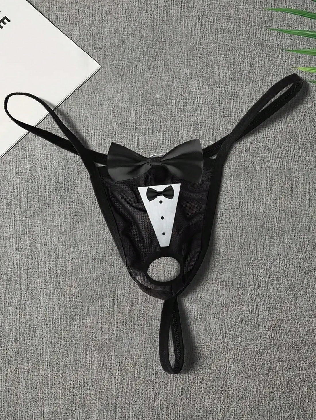 Men's black sheer mesh thong underwear with Halloween bow print pattern, bow decor, and cut-out details