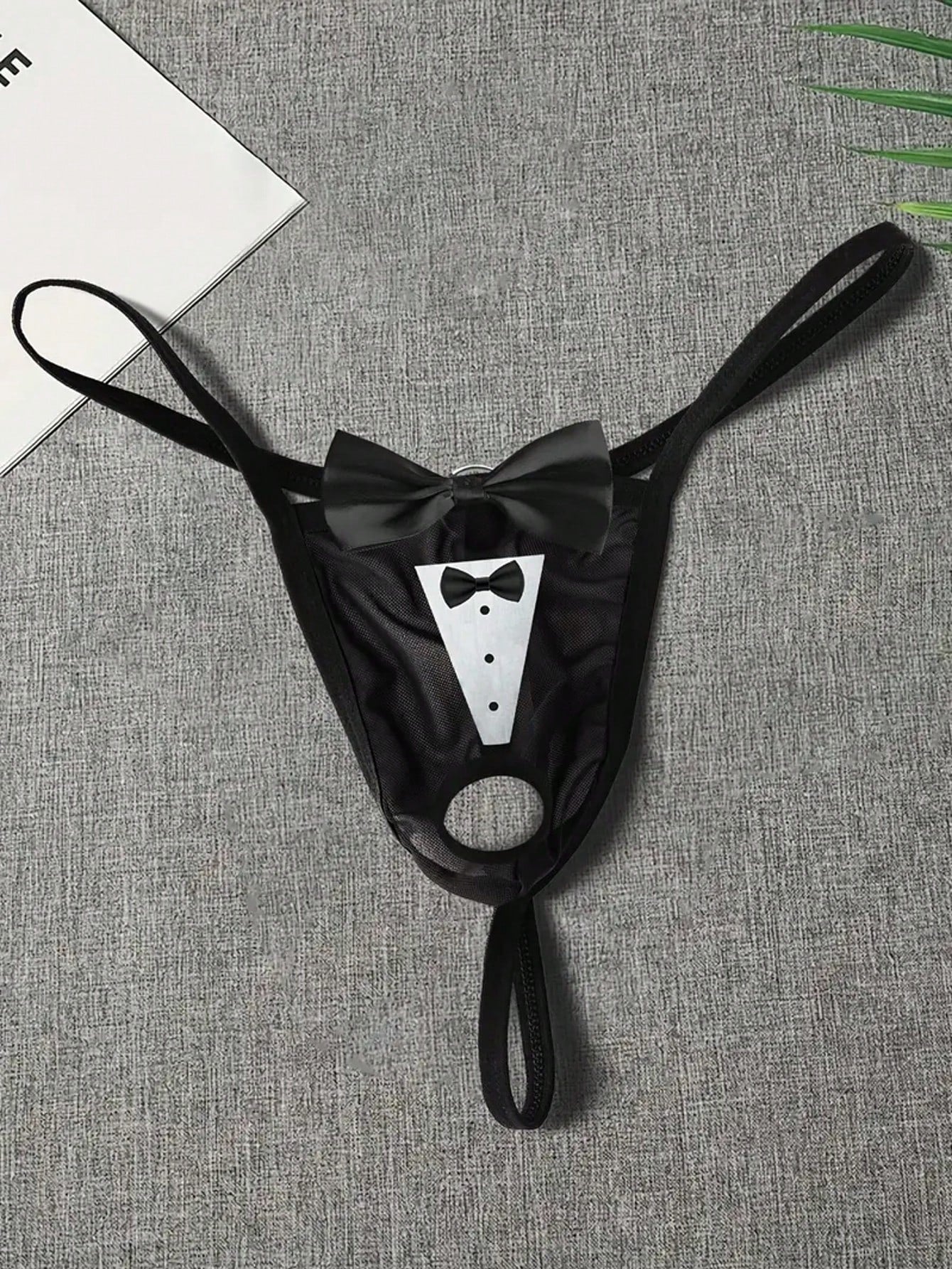 Men's black sheer mesh thong underwear with Halloween bow print pattern, bow decor, and cut-out details