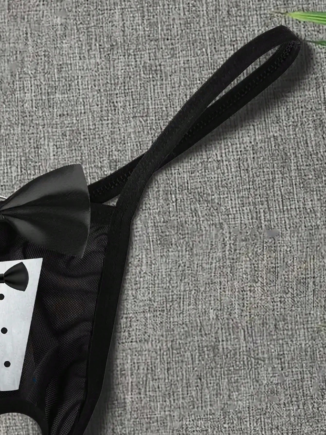 Men's black sheer mesh thong underwear with Halloween bow print pattern, bow decor, and cut-out details