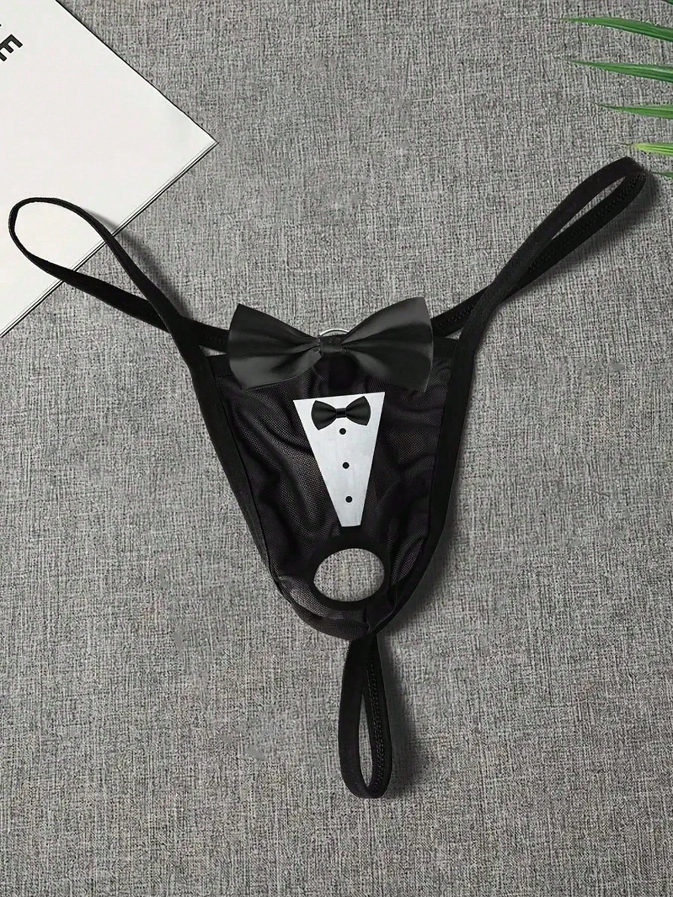 Men's black sheer mesh thong underwear with Halloween bow print pattern, bow decor, and cut-out details