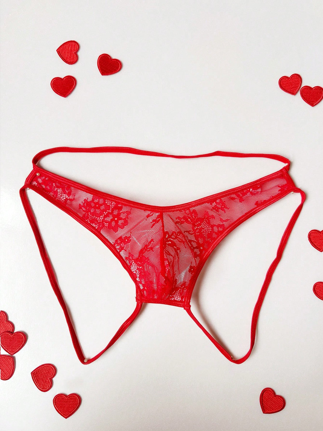 Men's red hollow-out lace jockstrap thong with geometric semi-sheer design, low-rise fit, and backless style