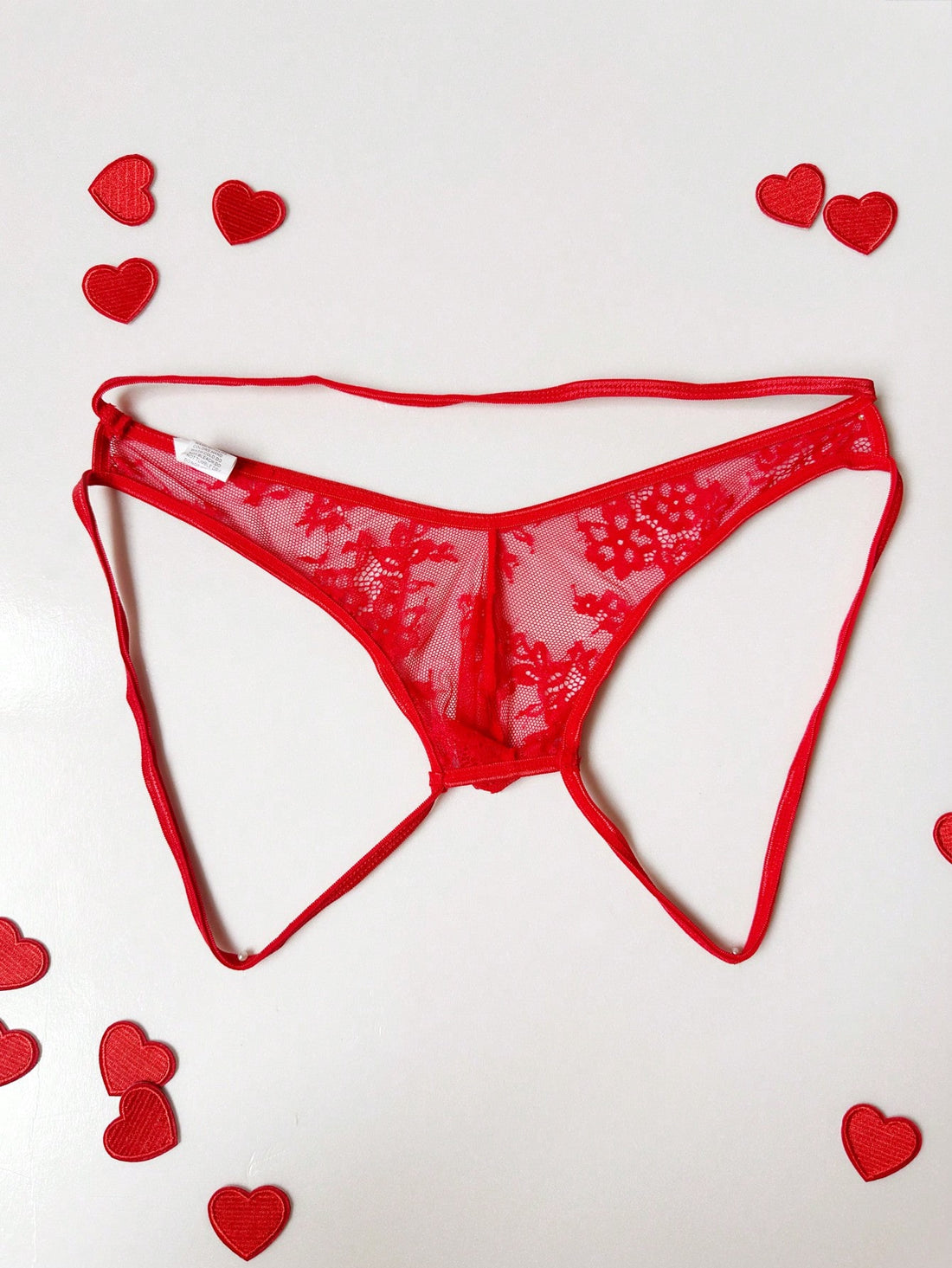 Men's red hollow-out lace jockstrap thong with geometric semi-sheer design, low-rise fit, and backless style