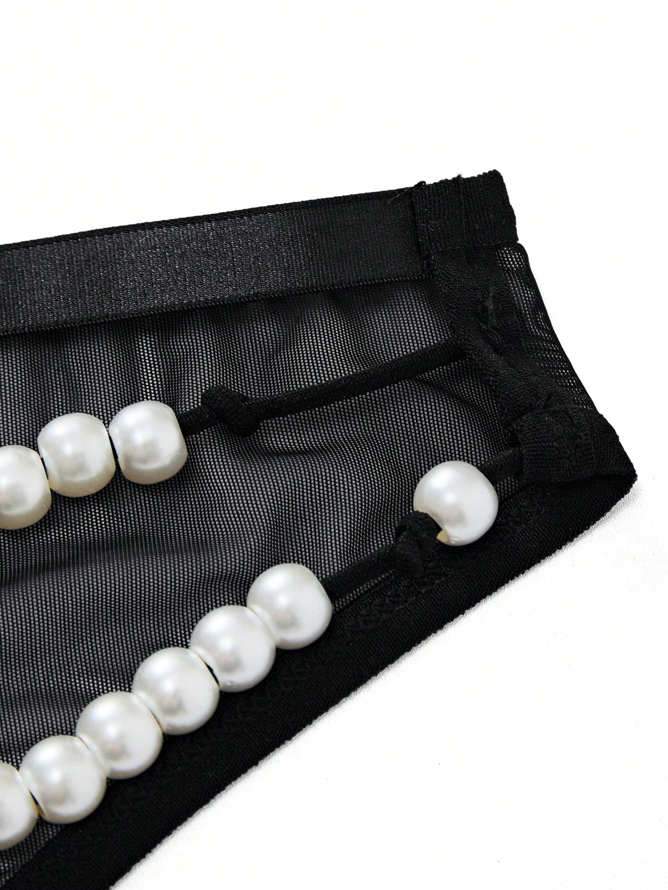 Men's black low-rise briefs with bow tie and pearl decor, colorblock styling, semi-sheer unlined body, and 3D pouch design.