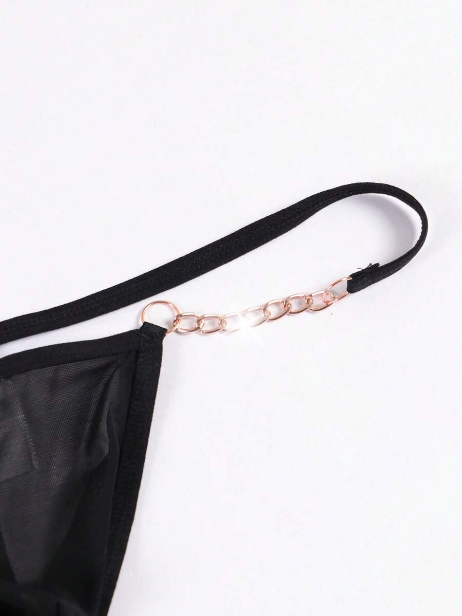 Black men's low rise thong underwear featuring semi-sheer knitted fabric, cut out design, contrast binding, and metallic chain decor.