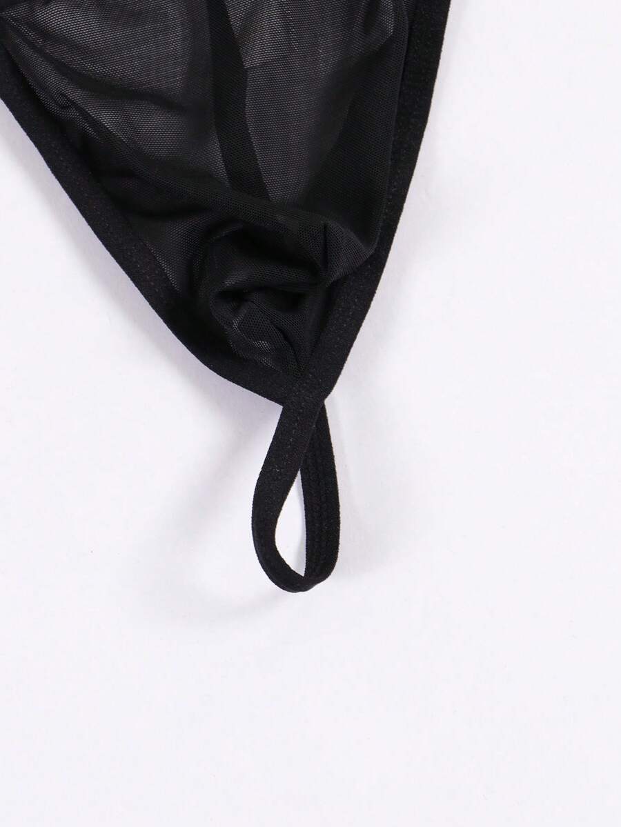 Black men's low rise thong underwear featuring semi-sheer knitted fabric, cut out design, contrast binding, and metallic chain decor.