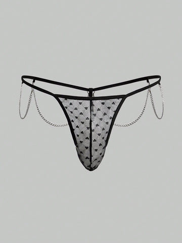 Men's black sheer mesh low-rise thong underwear with heart-shaped hollow-out design, geometric pattern, ring detail, and chain accent