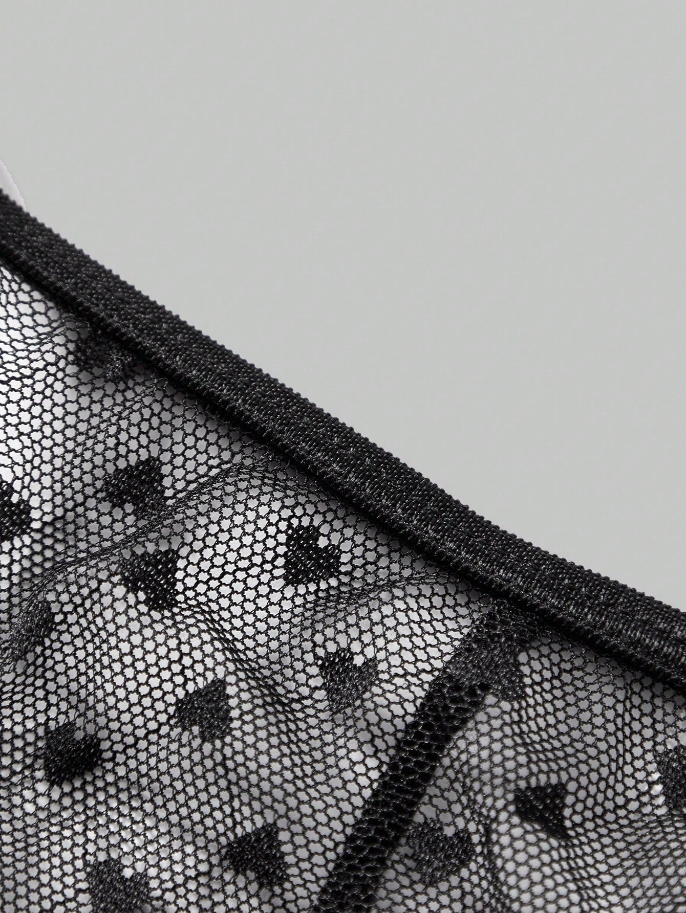 Men's black sheer mesh low-rise thong underwear with heart-shaped hollow-out design, geometric pattern, ring detail, and chain accent
