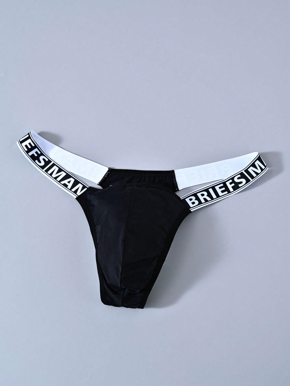 Men's solid color thong underwear with a letter waistband, textured pattern, tape detail, and mid-rise fit