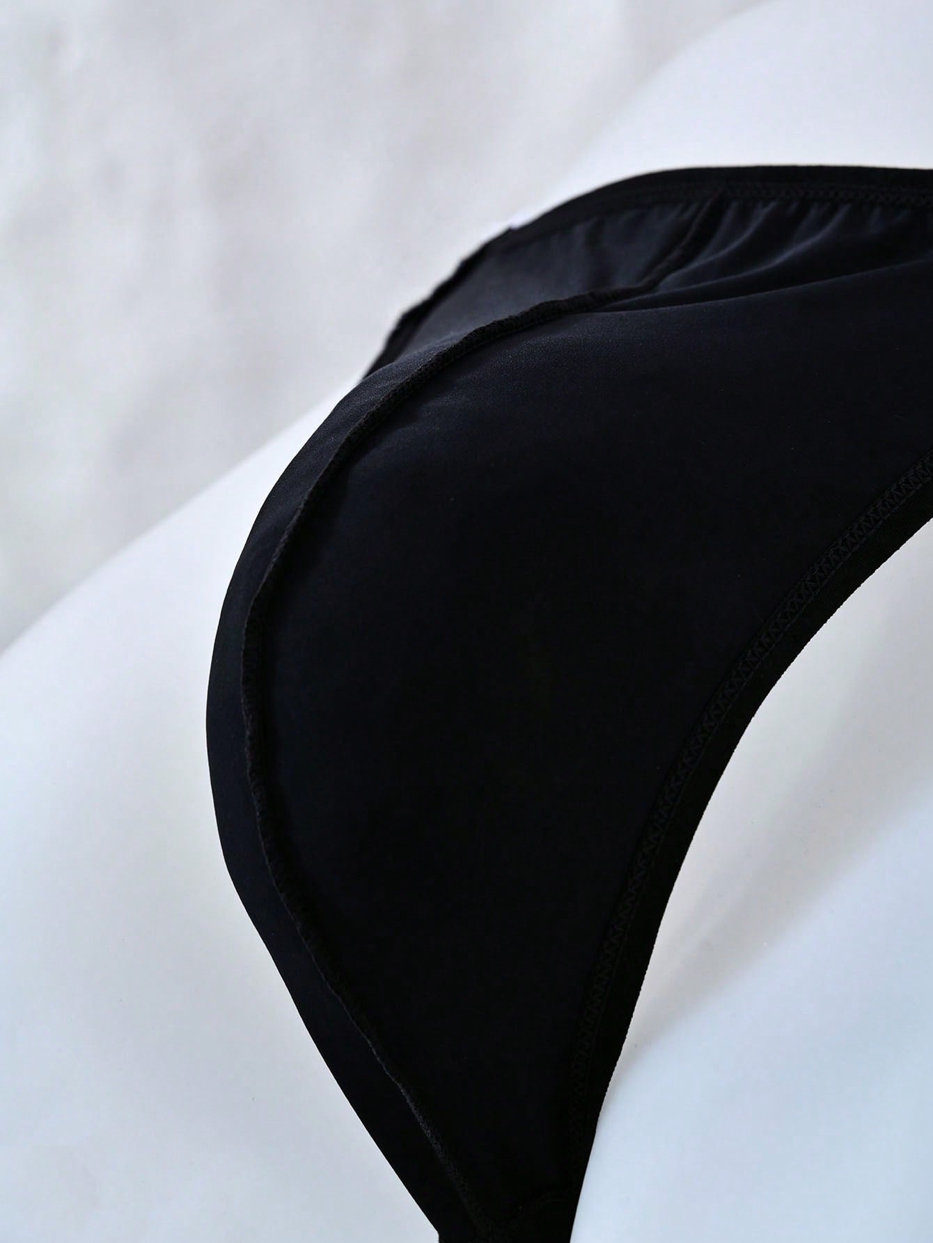 Men's solid color thong underwear with a letter waistband, textured pattern, tape detail, and mid-rise fit
