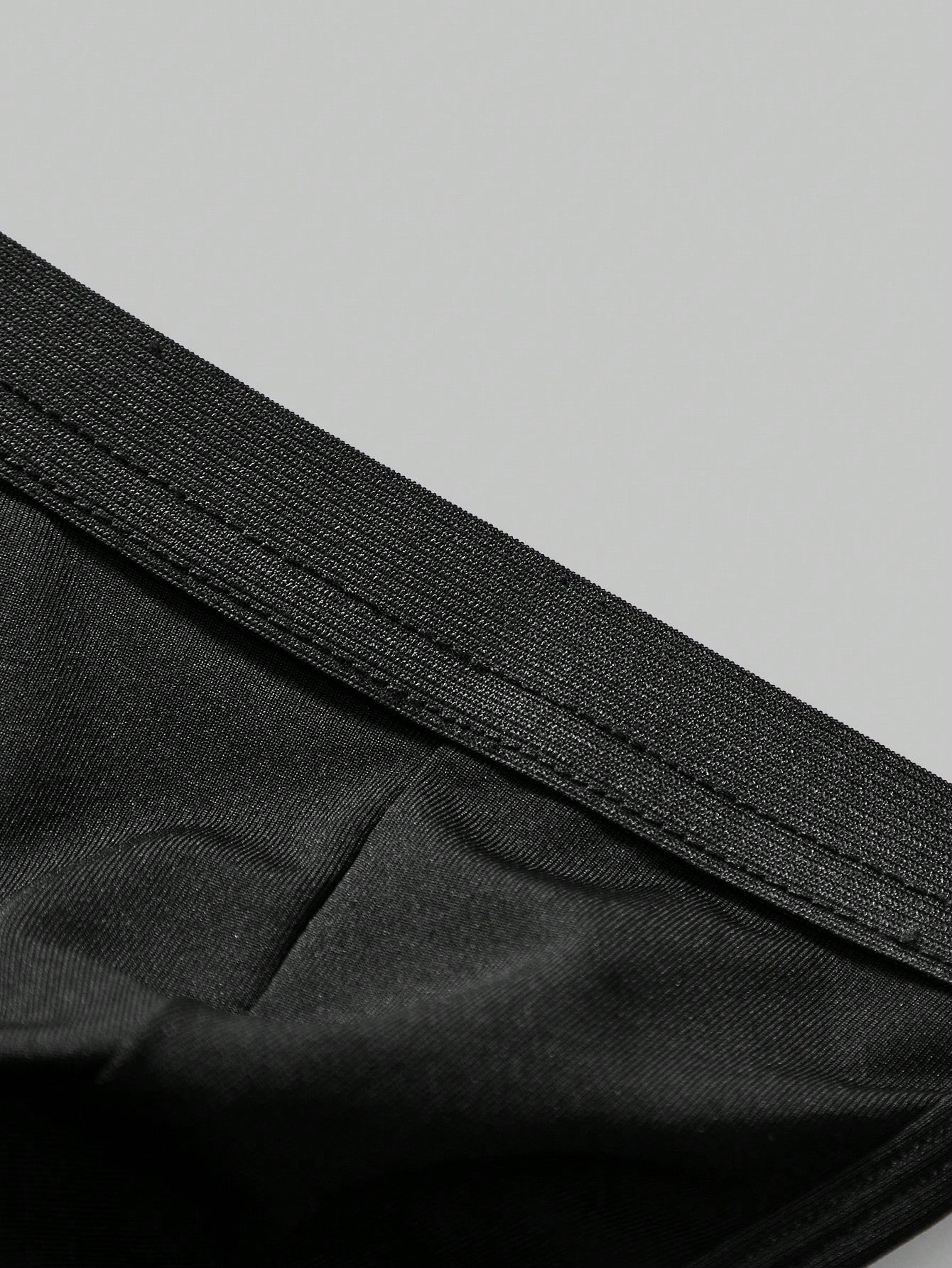 Men's black low-rise thong underwear with a plain solid color design