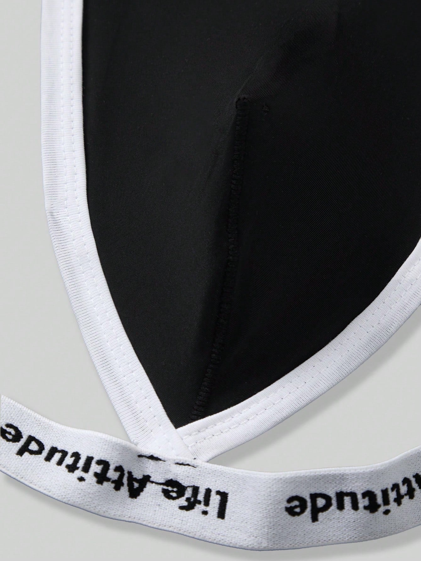 Men's black low-rise thong underwear with tape detail and letter and striped pattern