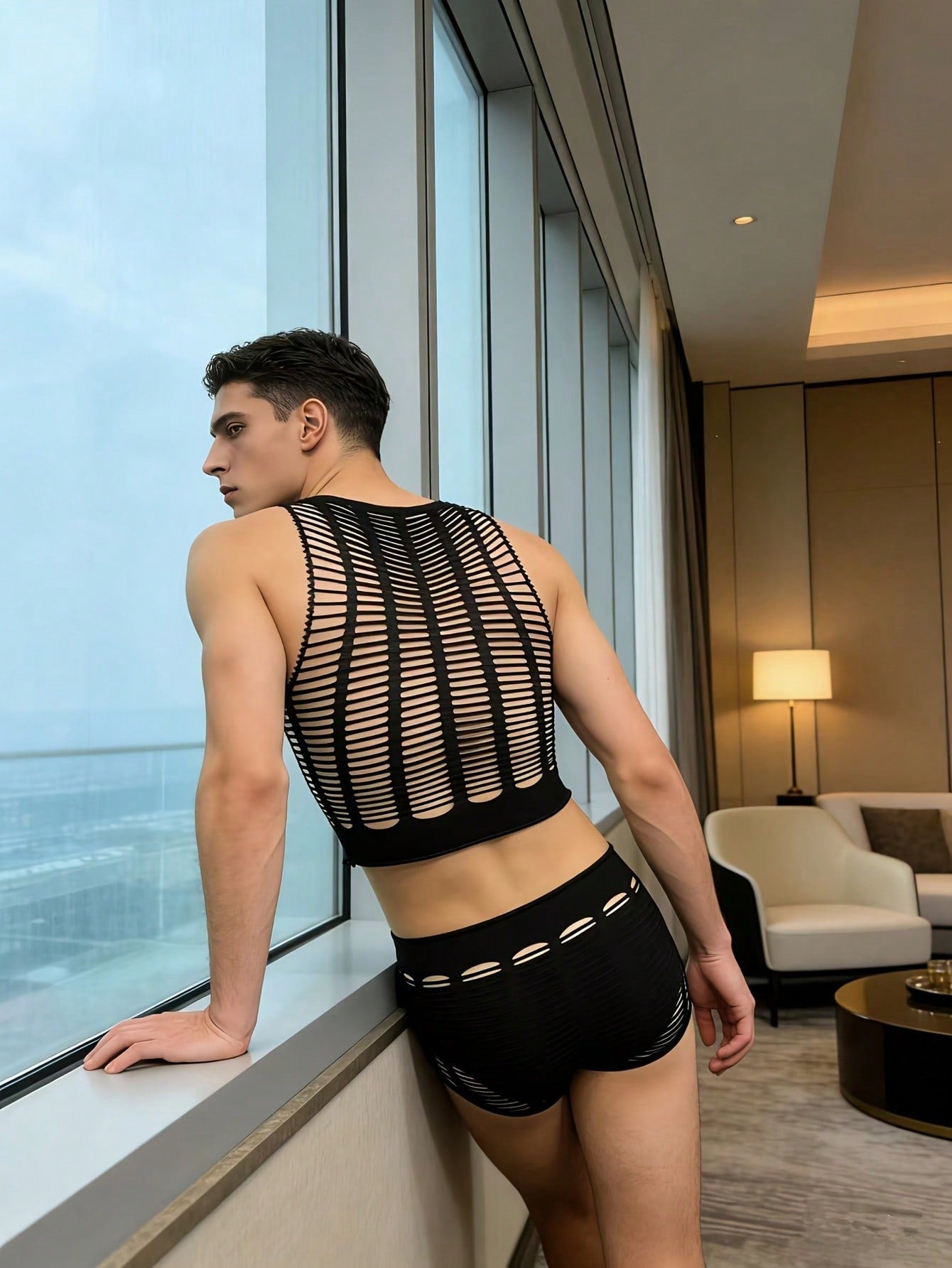Men's black sheer fishnet 2-piece lingerie set with a round-neck short top and mid-rise thong-style boyshorts featuring a striped hollow-out knit design.