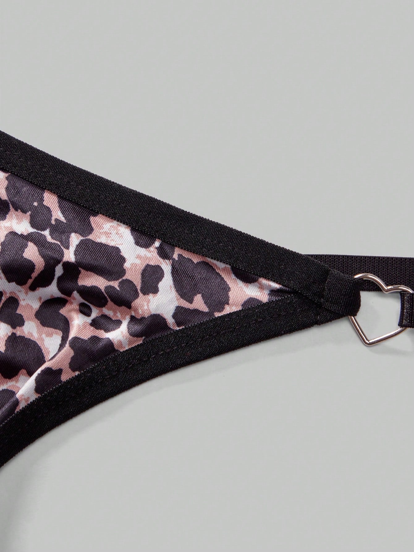 Men's multicolor thong underwear with leopard print, rhinestone heart decor, ring detail, low-rise fit, and sheer knitted fabric.