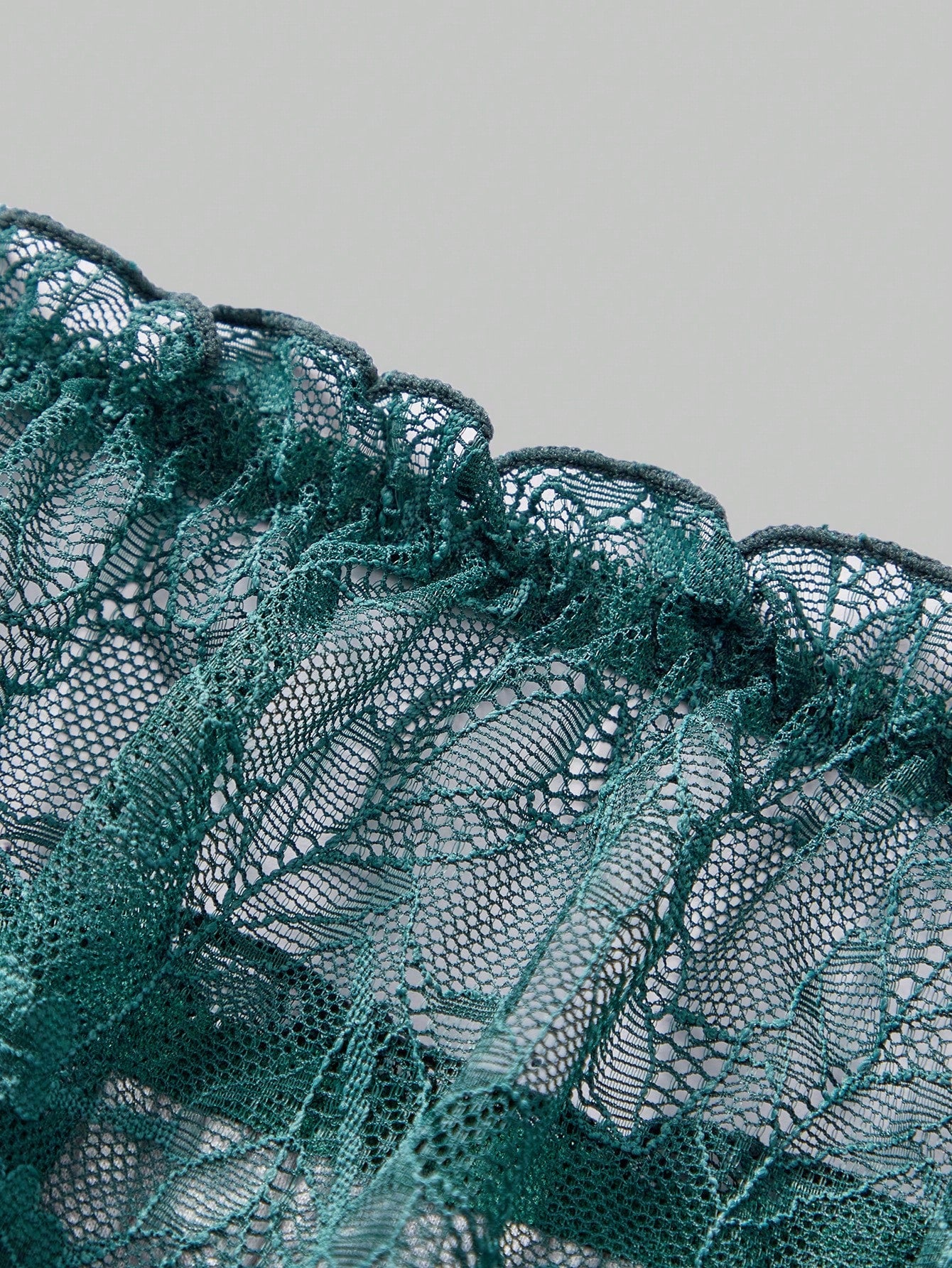 Men's dark green low-rise thong underwear with contrast lace, semi-sheer detailing, and random print design.
