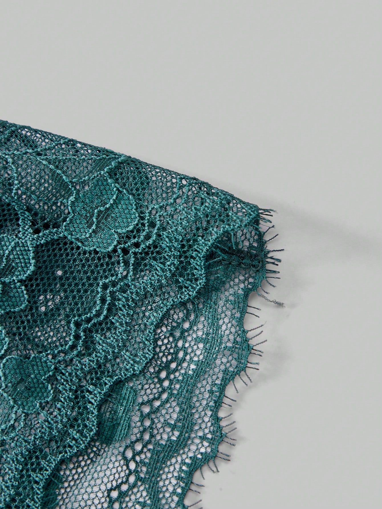 Men's dark green low-rise thong underwear with contrast lace, semi-sheer detailing, and random print design.