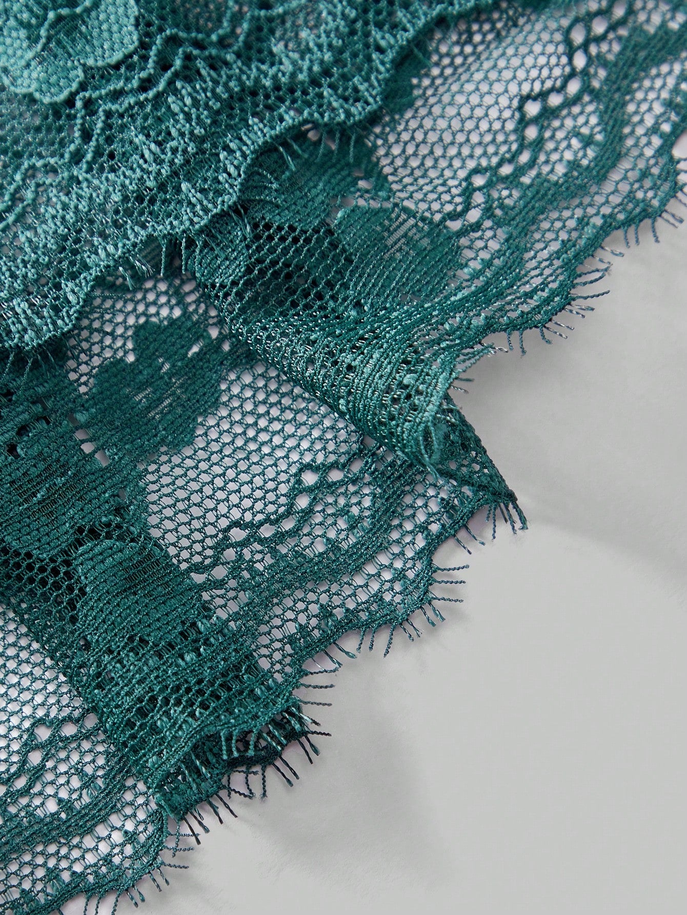 Men's dark green low-rise thong underwear with contrast lace, semi-sheer detailing, and random print design.