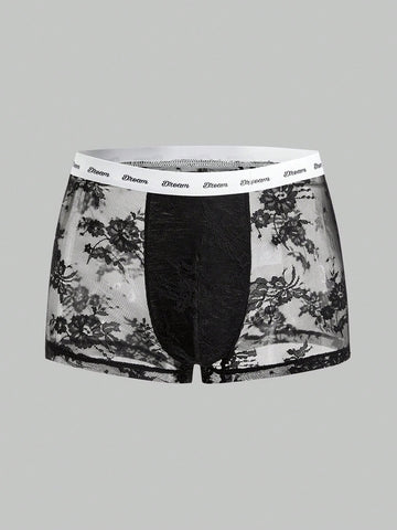 Men's black and white lace trim briefs with tape details and letter and plant pattern, shown as a short regular-fit underwear style.