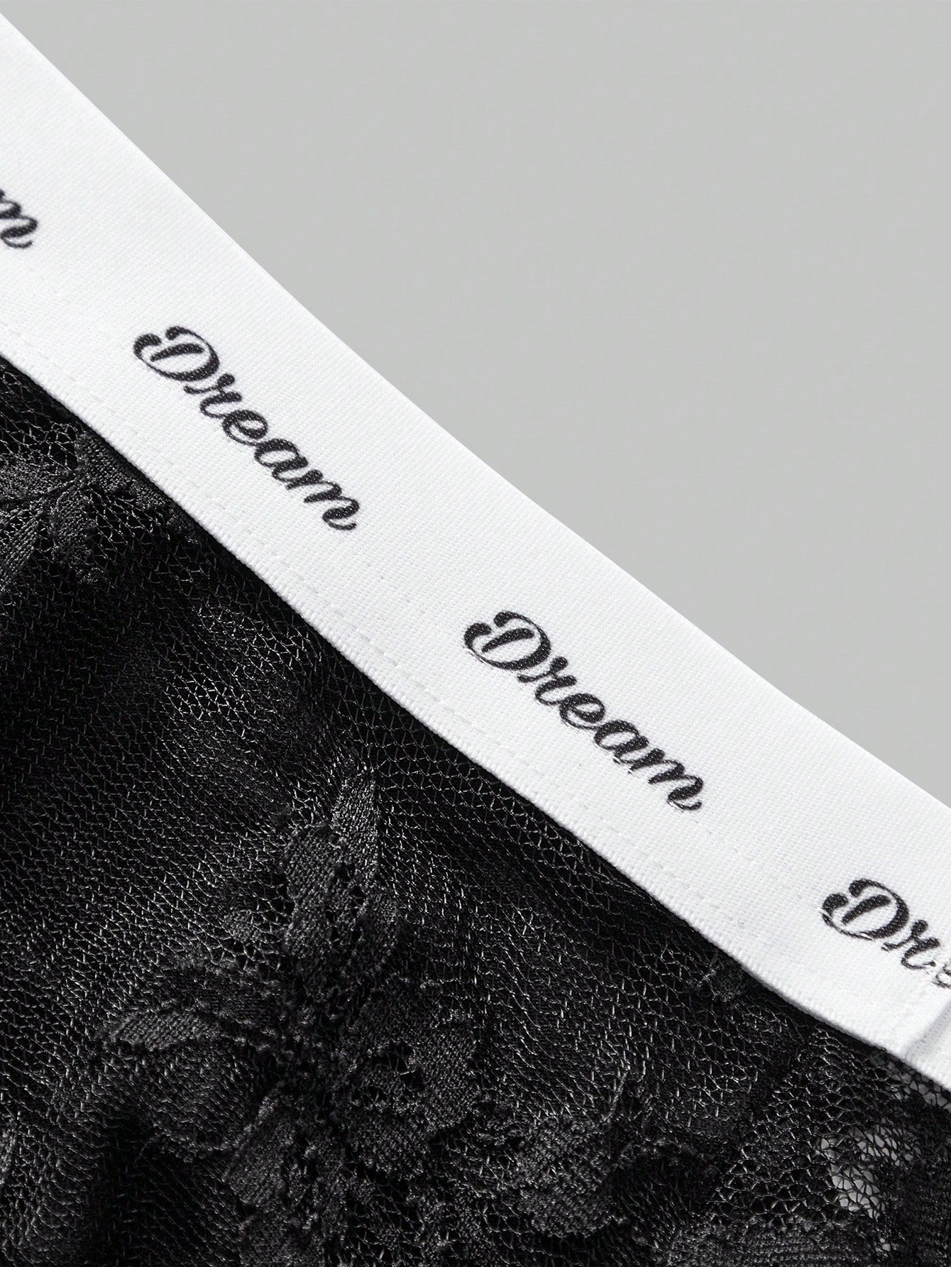 Men's black and white lace trim briefs with tape details and letter and plant pattern, shown as a short regular-fit underwear style.