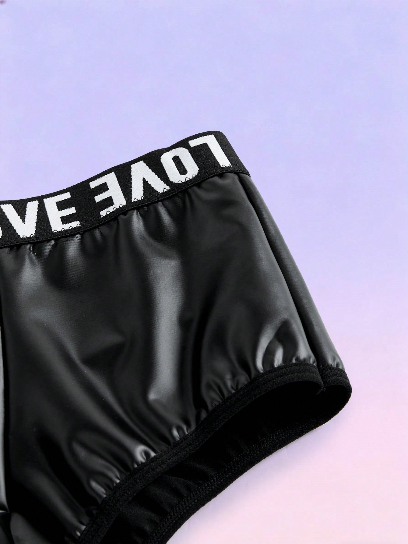 Black men's mid-rise briefs with letter woven strap, backless knot and tape details, and chain necklace