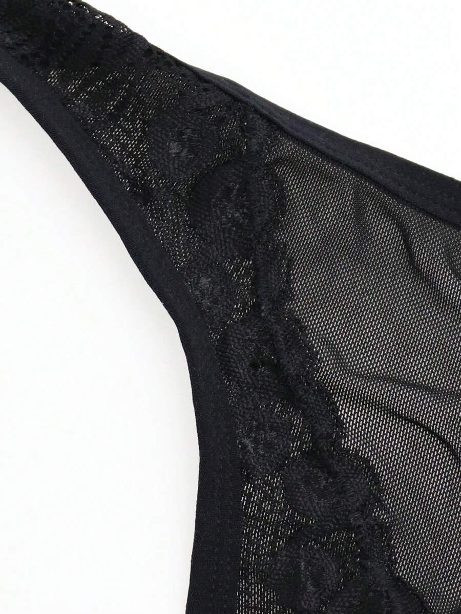 Black mid-rise mesh briefs for men featuring a hollow lace design and colorblock pattern.