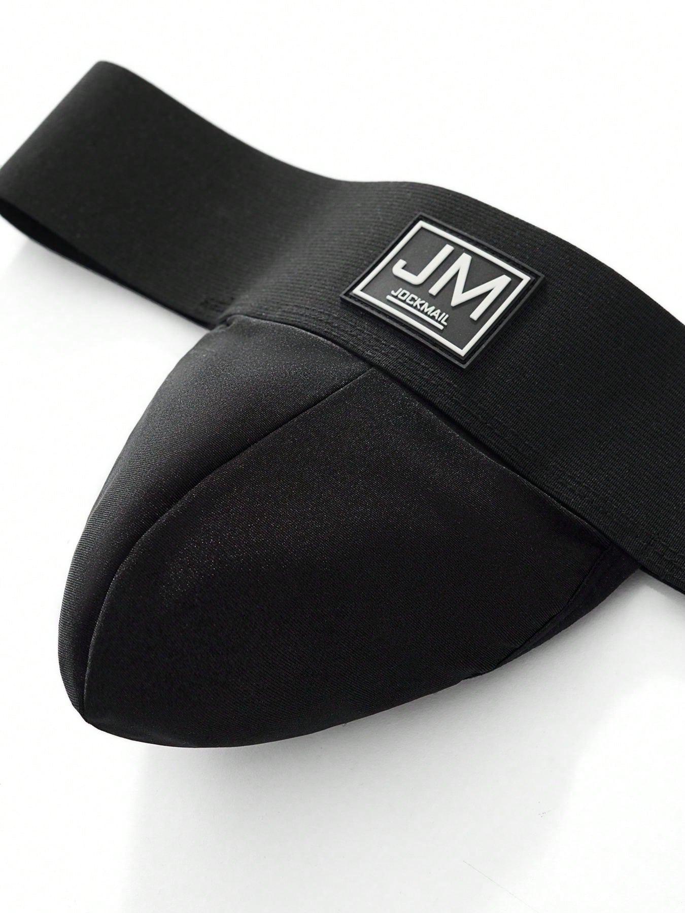 Men's black low-rise thong underwear with wide waistband and letter pattern, made from medium-stretch fabric.