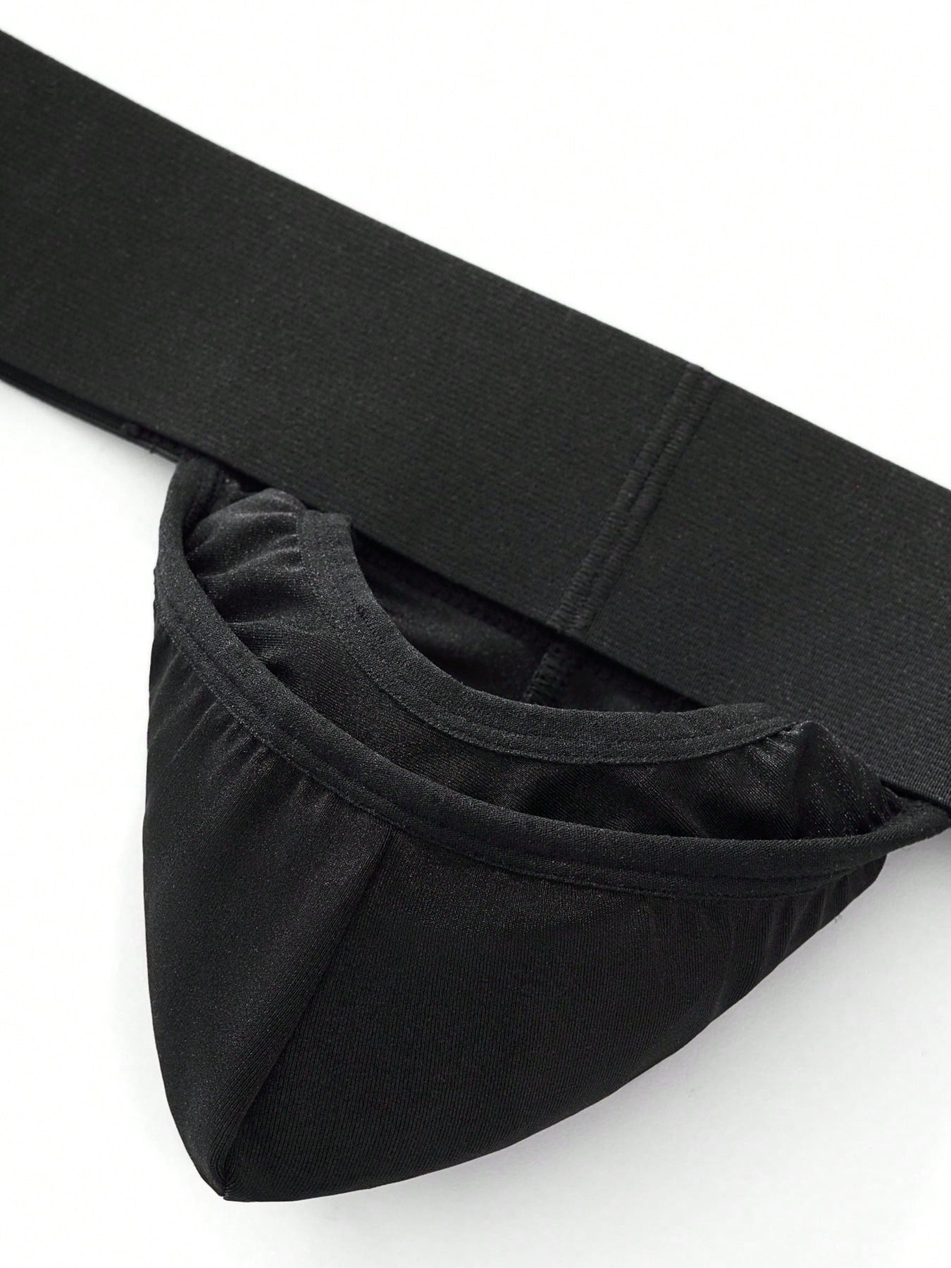 Men's black low-rise thong underwear with wide waistband and letter pattern, made from medium-stretch fabric.