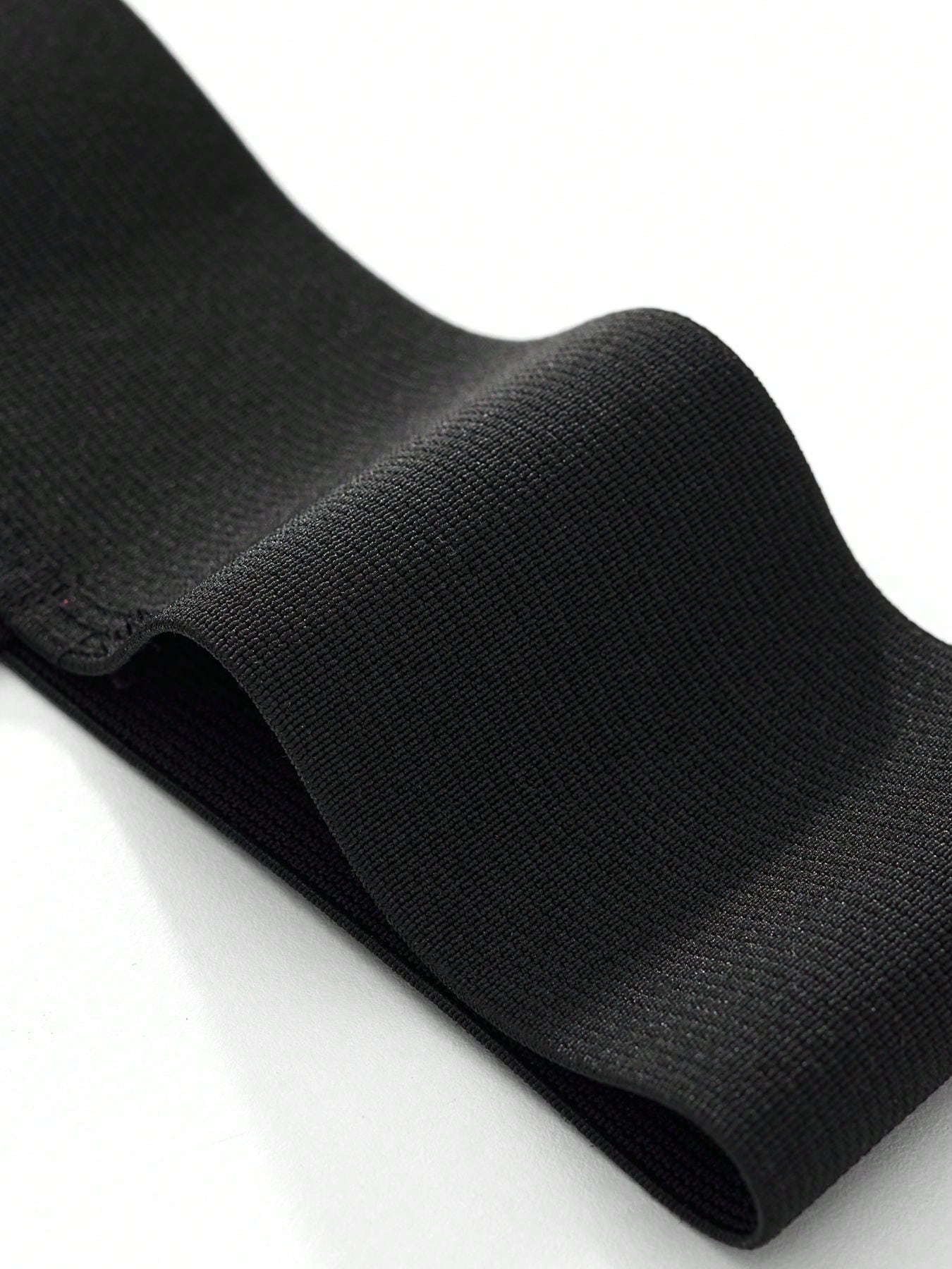 Men's black low-rise thong underwear with wide waistband and letter pattern, made from medium-stretch fabric.