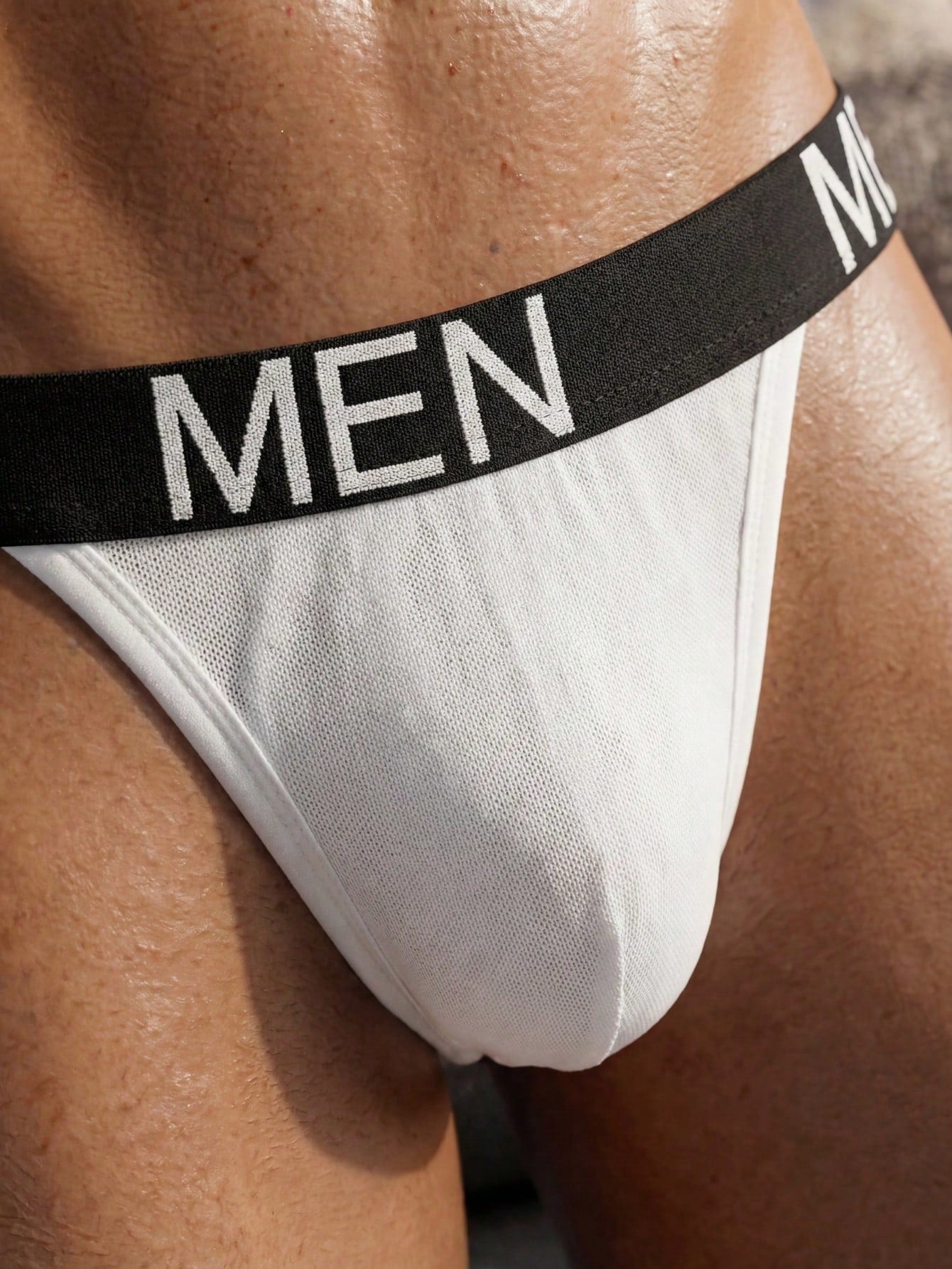 Men's black low-rise jockstrap briefs made from striped mesh fabric with a slim fit design