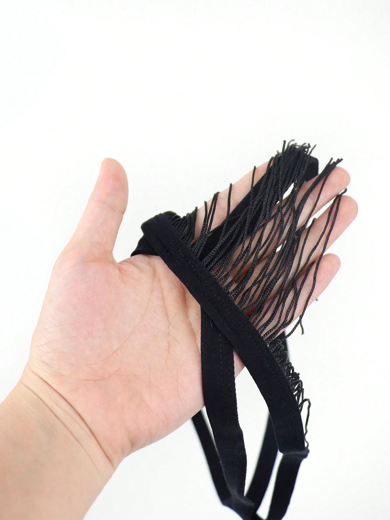 Men's black low-rise thong underwear with fringe detail, plain knitted fabric, and a non-sheer finish