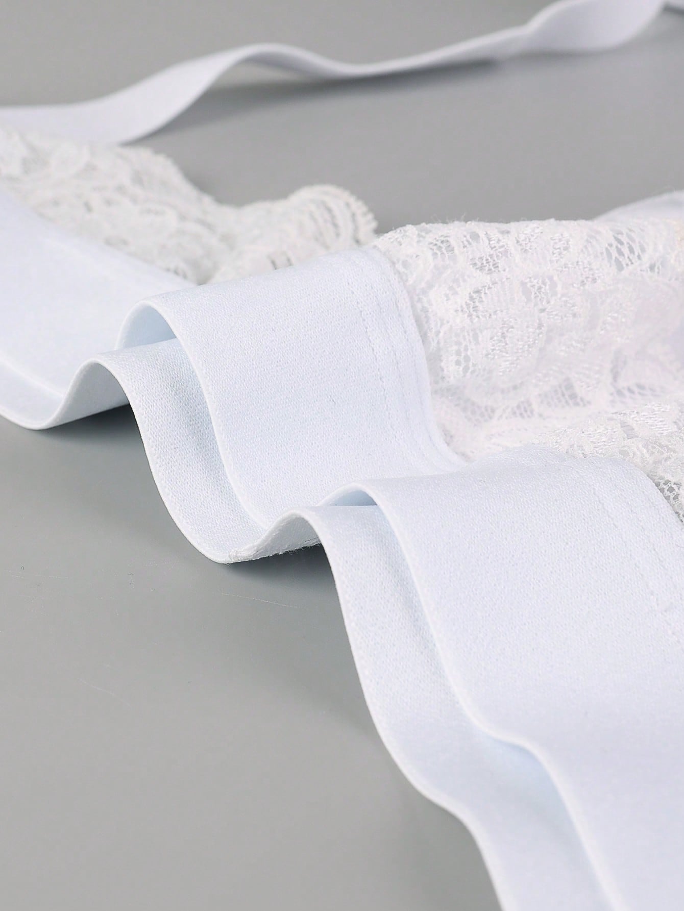 Men's white low-rise thong underwear with contrast lace detail and mesh fabric