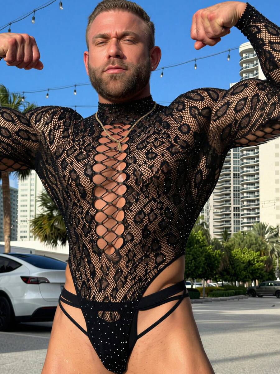 A man wearing a black hollow out rhinestone long jumpsuit featuring a stand collar and sheer knitted fabric.