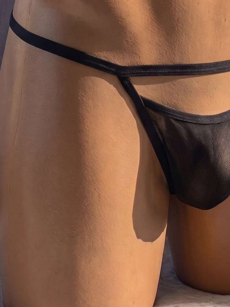 Men's black low-rise hollow mesh T-back thong underwear featuring ring detail.